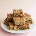 Sliced blondies on a wooden cutting board, showcasing a golden-brown color with visible chocolate chips and nuts.